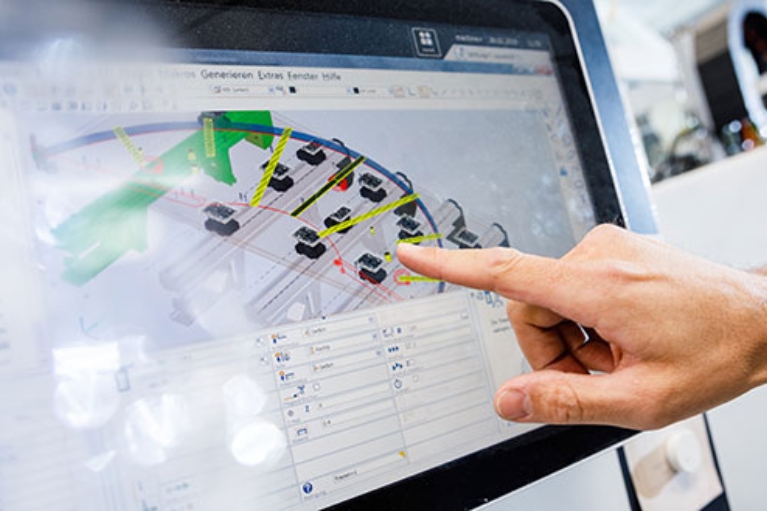 Ein Finger zeigt auf einen Monitor, auf dem eine technische Zeichnung zu sehen ist.