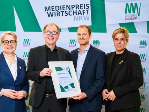Leonard Knollenborg und Jürgen Salz gewinnen Platz 1 des MEDIENPREIS WIRTSCHAFT NRW 2025 und 5.000 Euro mit ihrem Beitrag „Das Experiment“. Sie erhalten die Auszeichnung von Gabriela Pantring, designierte Vorsitzende des Vorstands der NRW.BANK, und Wirtschafts- und Klimaschutzministerin Mona Neubaur (Bild: NRW.BANK / Oliver Wachenfeld)