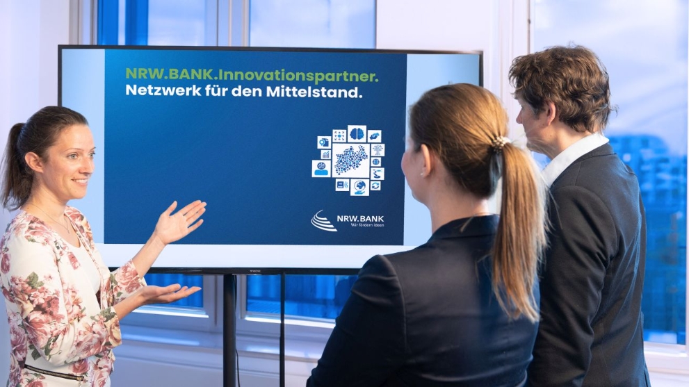 Eine Frau erklärt zwei Teilnehmenden in einem Workshop das Prinzip der NRW.BANK.Innovationspartner.