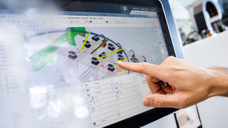 Eine Hand deutet auf einen Bildschirm, auf dem ein Plan einer technischen Anlage zu sehen ist.