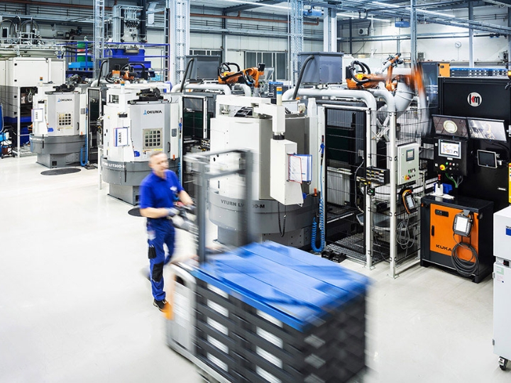 Halle des Automobilzulieferers Fischer und Kaufmann mit technischen Anlagen, ein Mann fährt mit einem Hubwagen.