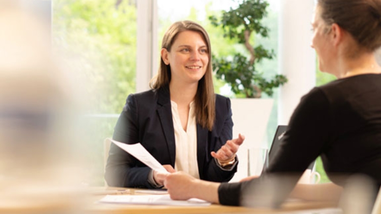 Beratungssituation mit zwei Frauen, die sich am Schreibtisch gegenüber sitzen