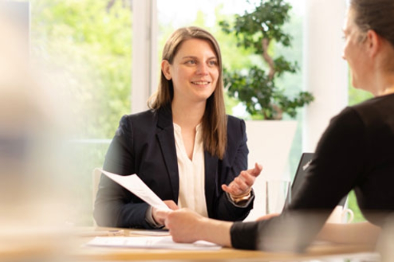 Beratungssituation mit zwei Frauen, die sich am Schreibtisch gegenüber sitzen