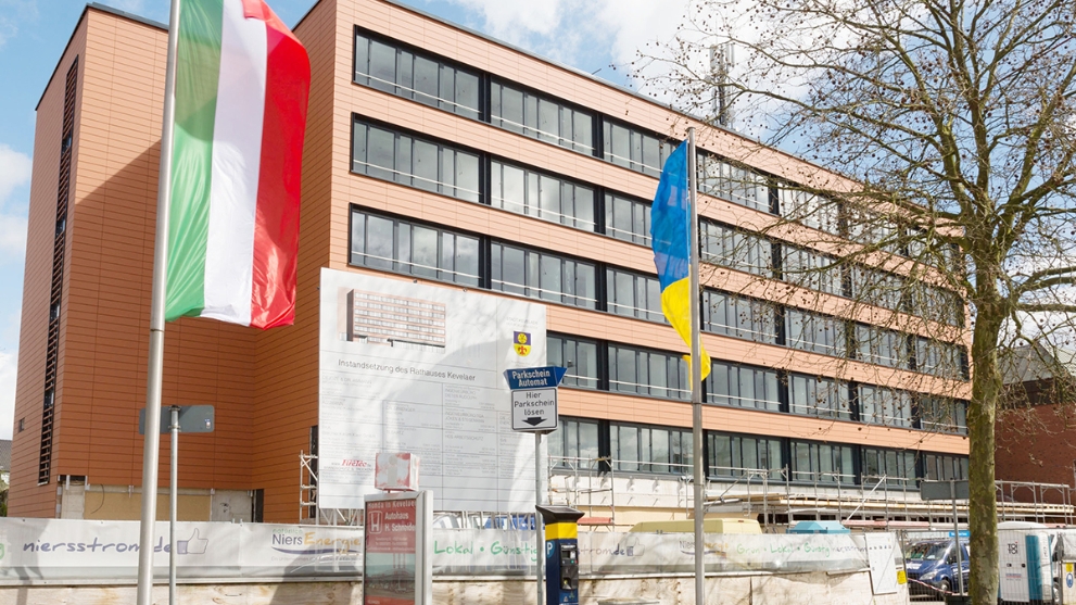 Ein kommunales Gebäude, an dem Baumaßnahmen durchgeführt werden, mit der NRW-Fahne im Vordergrund