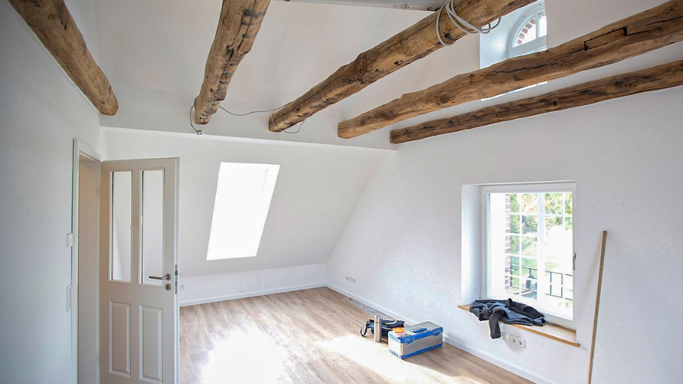 Heller Raum mit Holzboden und Naturbalken an der Decke