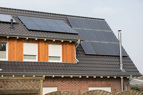 Das Bild ein Hausdach mit einer Solaranlage. Die NRW.BANK bietet Förderprogramme für Modernisierunung und energetische Sanierung an.
