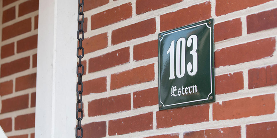 Eingangsbereich eines roten Ziegelhauses mit der Hausnummer 103.