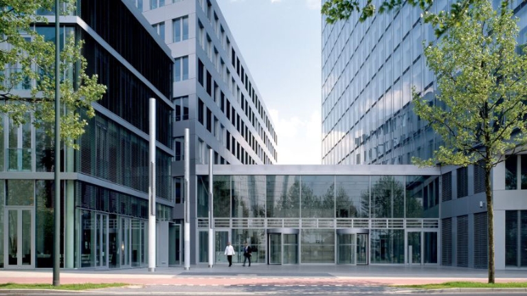 Der Eingangsbereich der NRW.BANK-Zentrale in Düsseldorf von außen, mit großer Fensterfront und Drehtüren