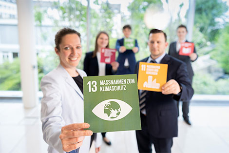 Employee holds the symbol for UN goal number 13: climate protection.