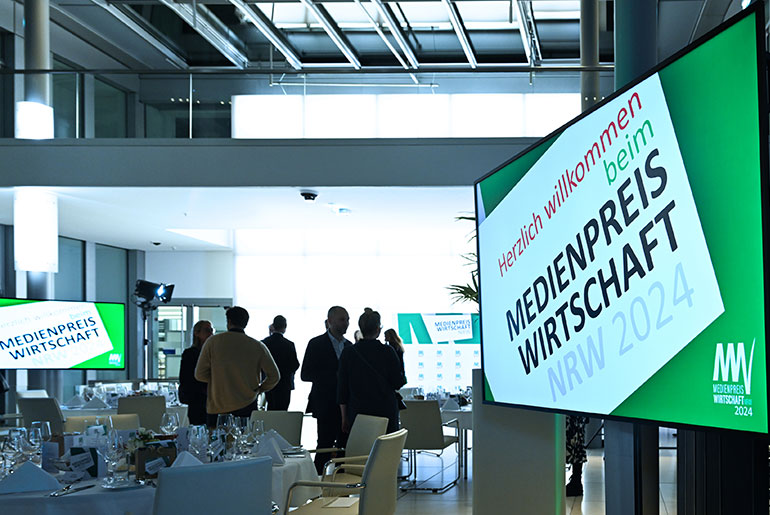 Ein Blick in das Foyer NRW.BANK mit Bildschirmen, auf den das Logo des Medienpreis abgebildet ist.