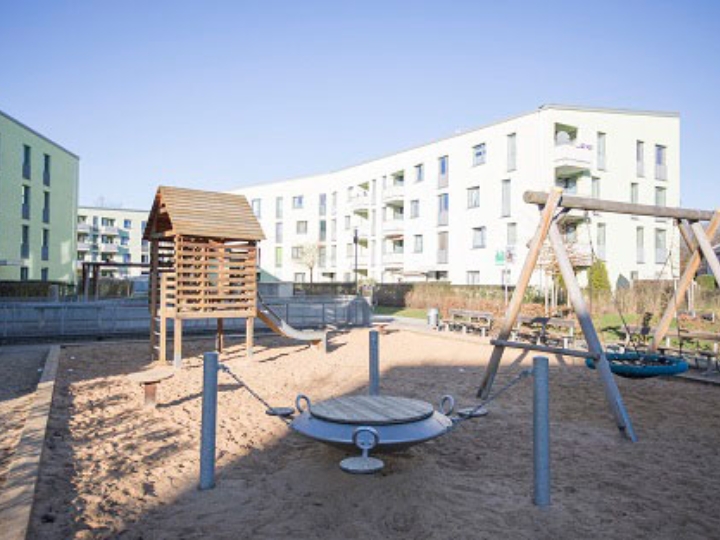 Modernes Mehrfamilienhaus von außen mit einem Spielplatz im Vordergrund