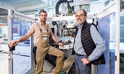 Jan und Josef Hüser, Geschäftsführer der Hüser Michels GmbH, vor einer großen Maschine in ihrer Firma