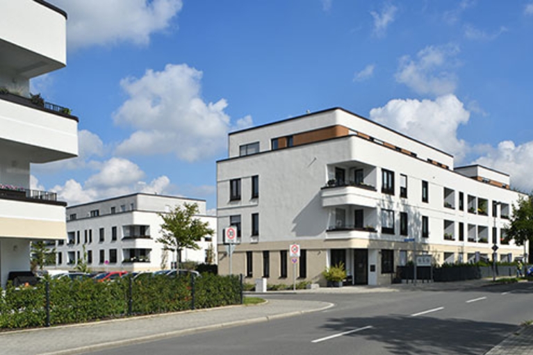 Eine Neubausiedlung mit heller Fassade und abgerundeteten Ecken