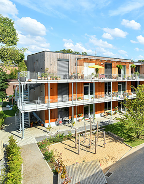 Innenhof des Wohnprojekts TRIALOG in Hilden mit Spielplatz und bunten Fahnengirlanden.