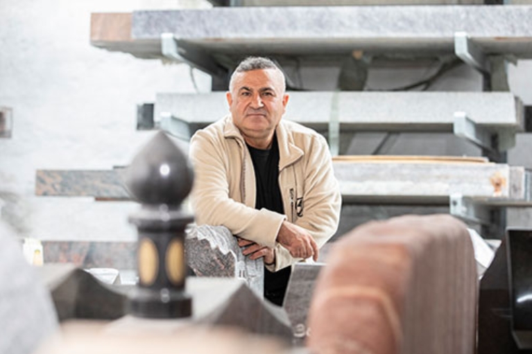 Hamid Osman lehnt an einem Grabstein vor großen Marmorplatten