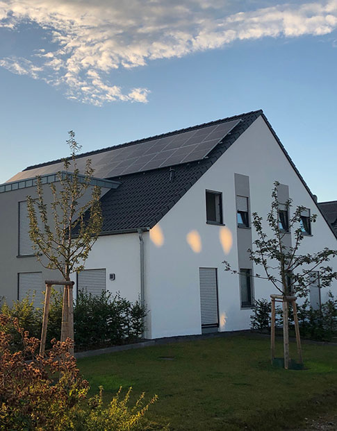 Ein Wohnhaus mit Solaranlagen auf dem Dach und Garten