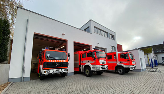 Drei Feuerwehrautos stehen in den Einfahrten eines Feuerwehrhauses