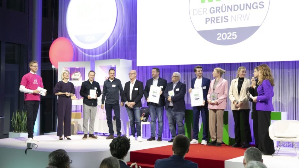 Die Gewinner von MUT - DER GRÜNDUNGSPREIS NRW 2025 bei der Preisverleihung mit den Moderatoren auf der Bühne