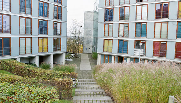 Ein Weg führt zwischen zwei Gebäuden eines Studentenwohnheims hindurch, seitlich des Weges Grünflächen.