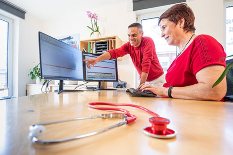 Sascha Jung und eine Mitarbeiterin vor zwei Computerbildschirmen