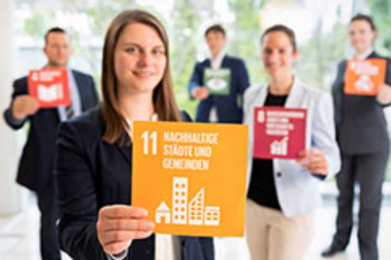 Mitarbeiter der NRW.BANK halten Karten mit Symbolen der Sustainable Development Goals hoch.