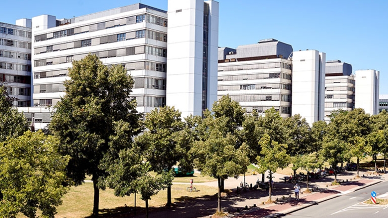 Der Gebäudekomplex der Universität Bielefeld mit einer Straße und Bäumen im Vordergrund