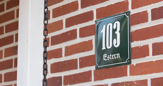 Ausschnitt einer roten Backsteinfassade mit der Hausnummer 103