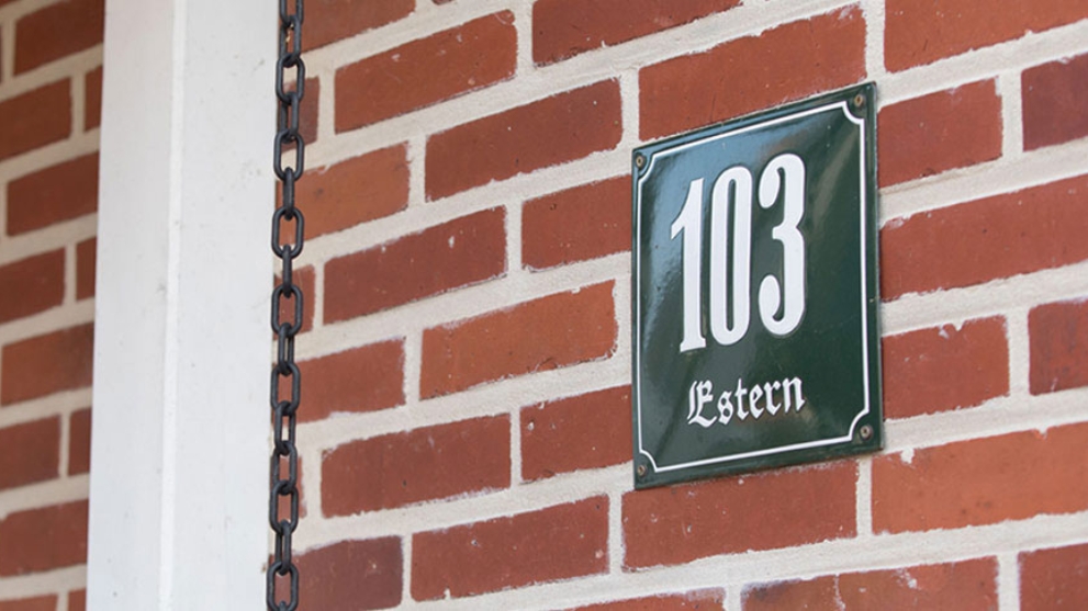 Ausschnitt einer roten Backsteinfassade mit der Hausnummer 103